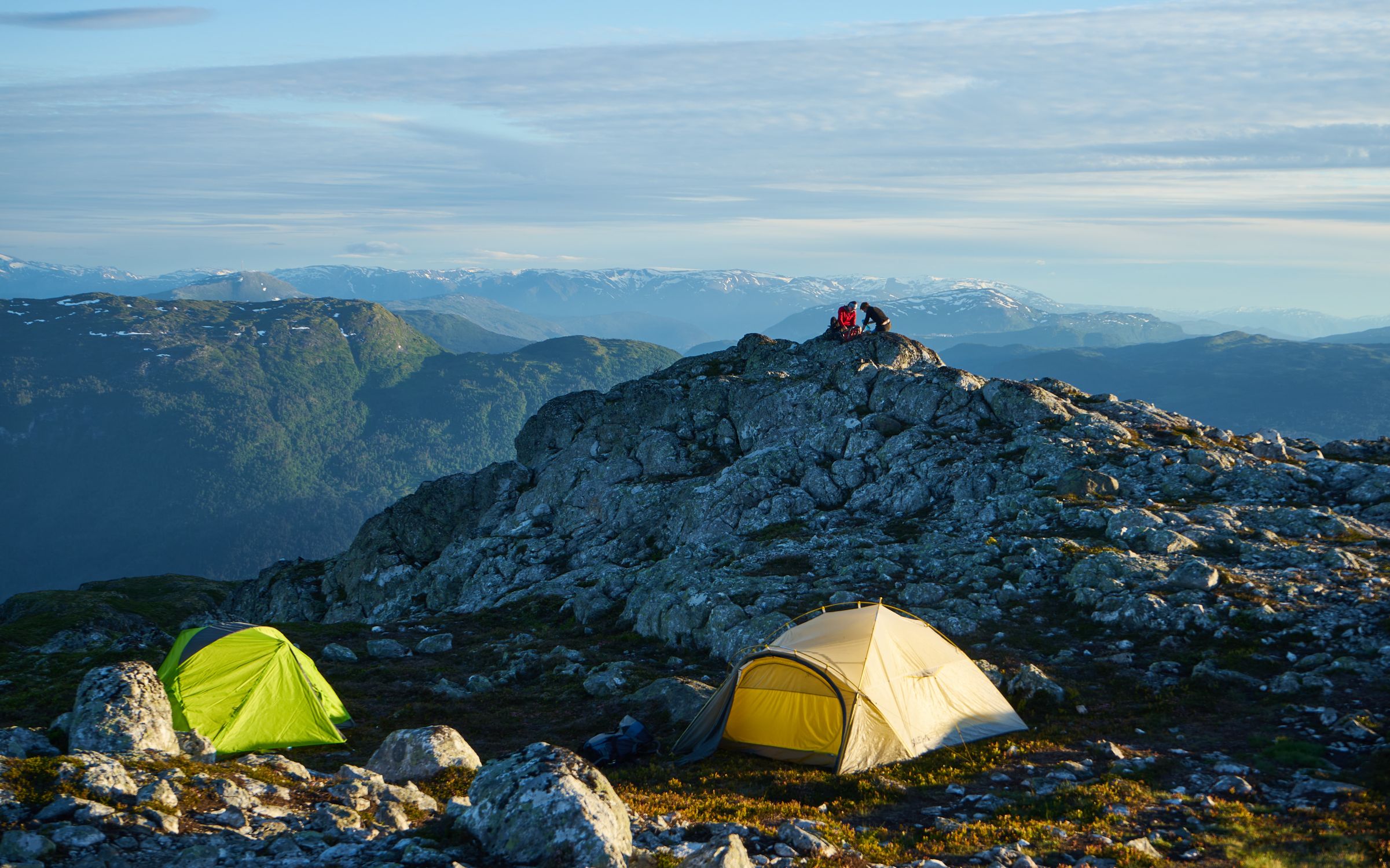Wilderness camping scene with tents on rocky alpine terrain under a clear sky Wilderness camping scene with tents on rocky alpine terrain under a clear sky