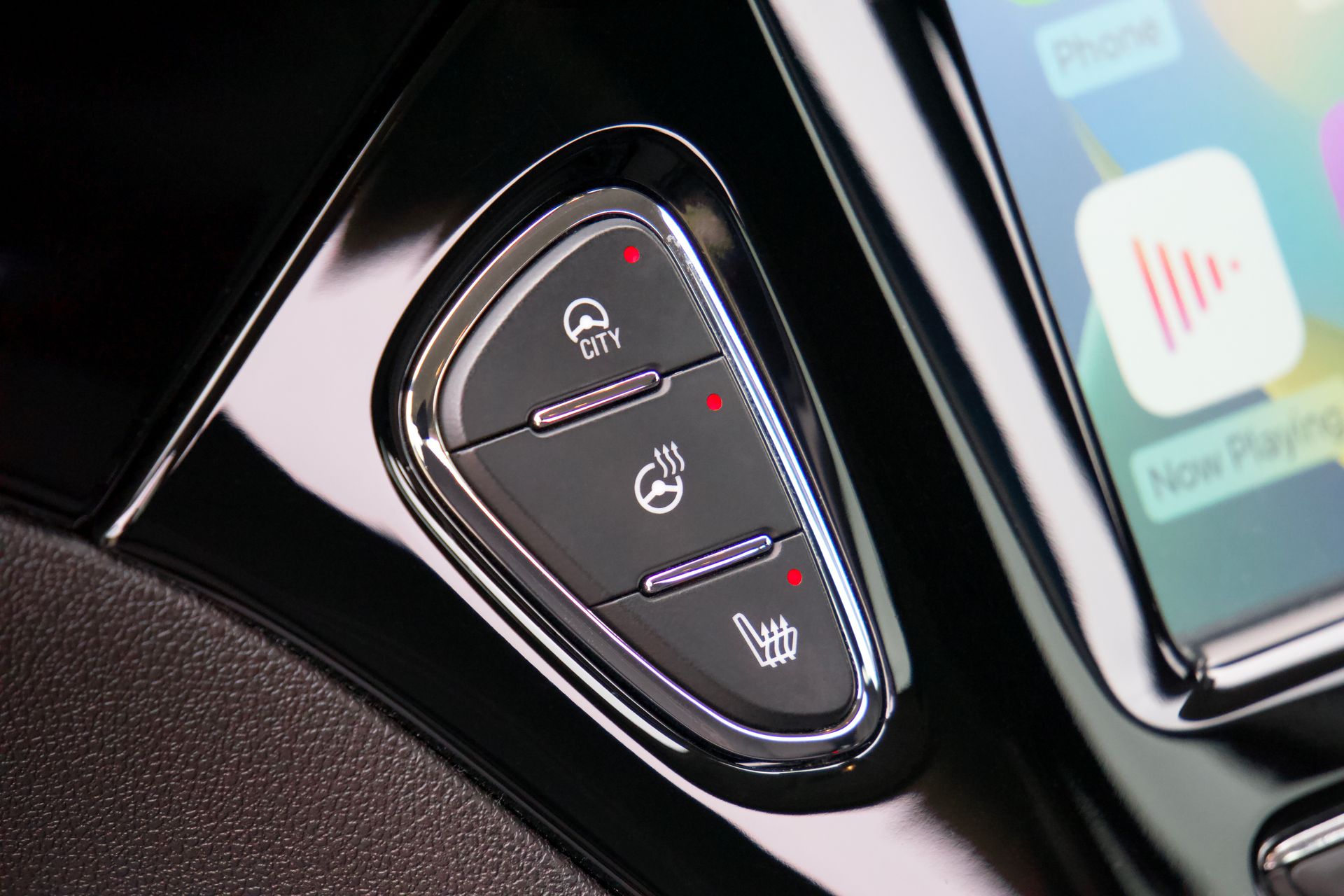 Detailed view of a car dashboard control panel with chrome buttons and glossy finish.