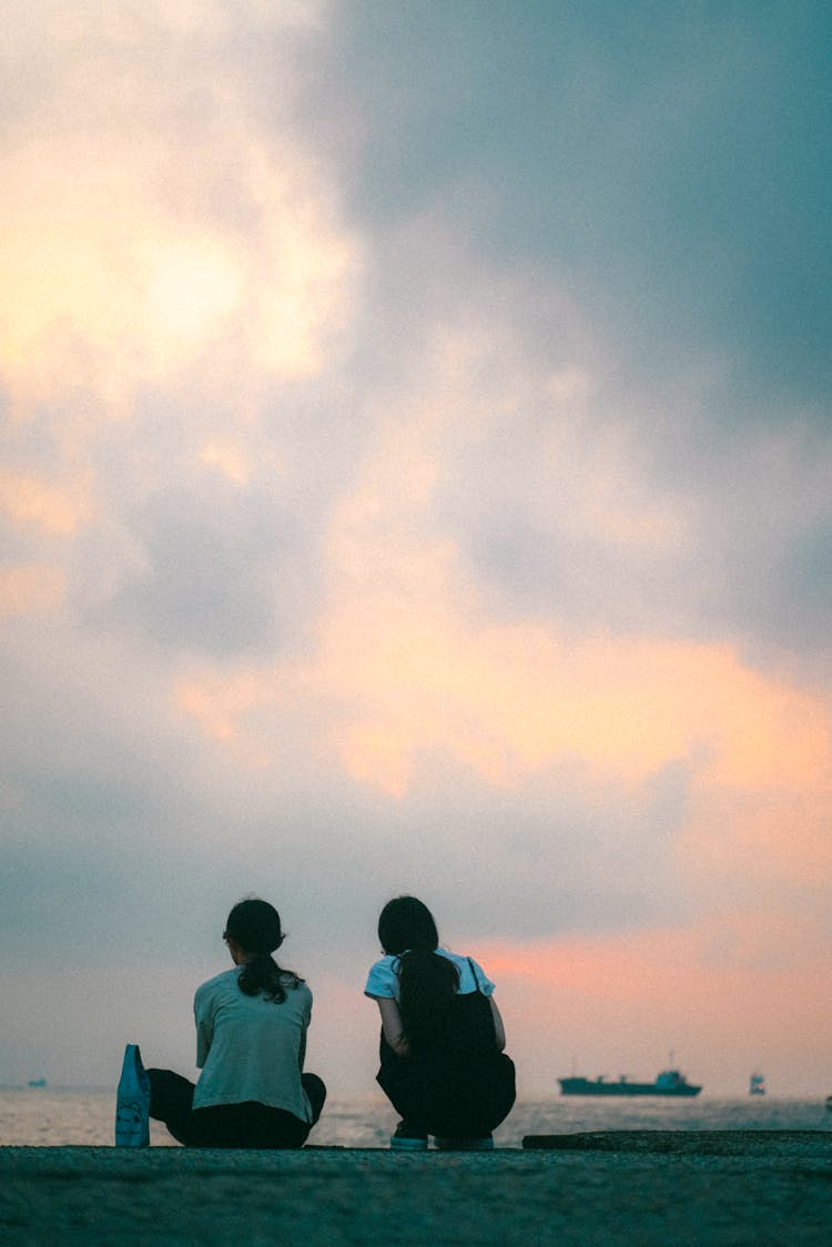 Girls Sitting In Harbor During Sunset 