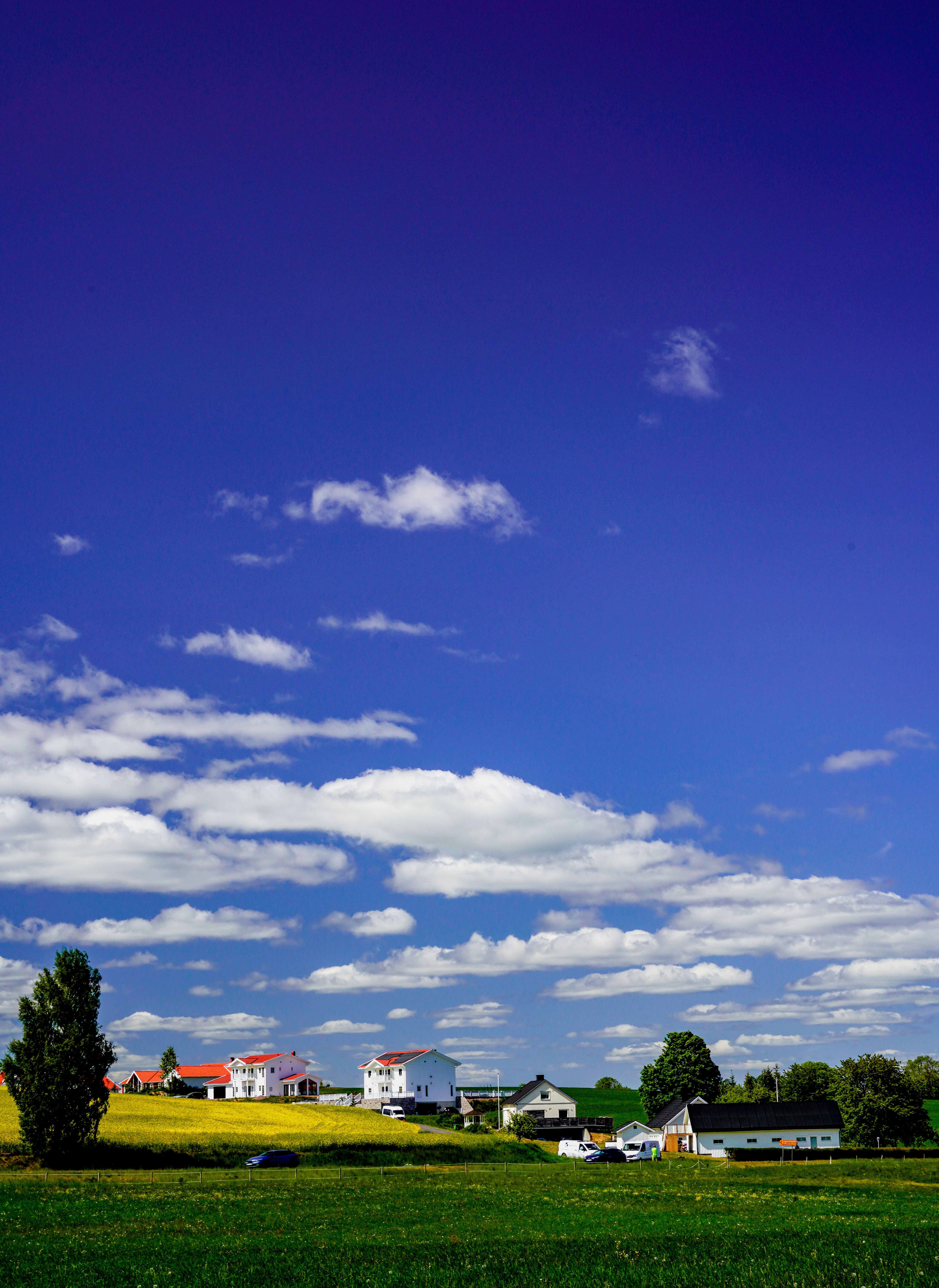 Beautiful rural landscape in Jönköping, Sweden, showcasing a clear blue sky and scattered clouds over a village.