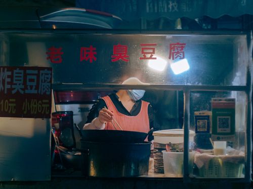 Free Street vendor serving tofu at night market. Urban food scene with artificial lighting. Stock Photo