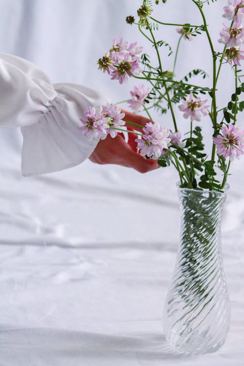 Woman Hand Touching Flowers in Glass Vase