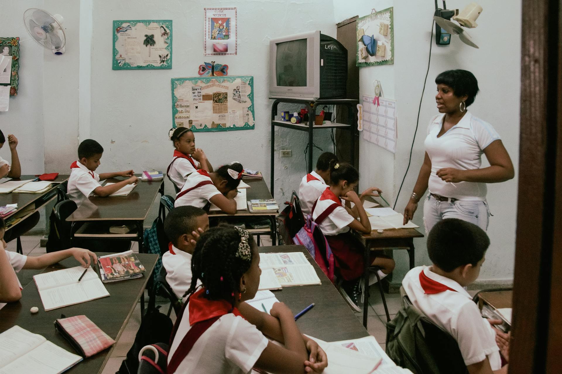 A classroom scene with children learning, guided by a teacher, indicative of an education setting.