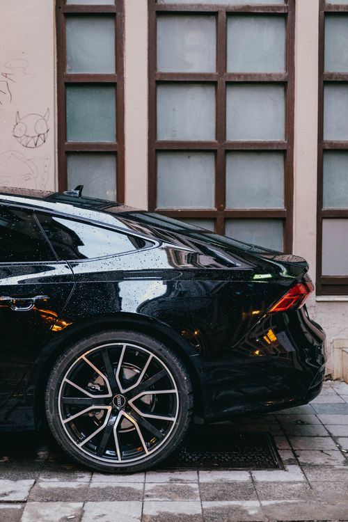 Free Raindrops on a sleek black car parked along a city street, modern and stylish look. Stock Photo