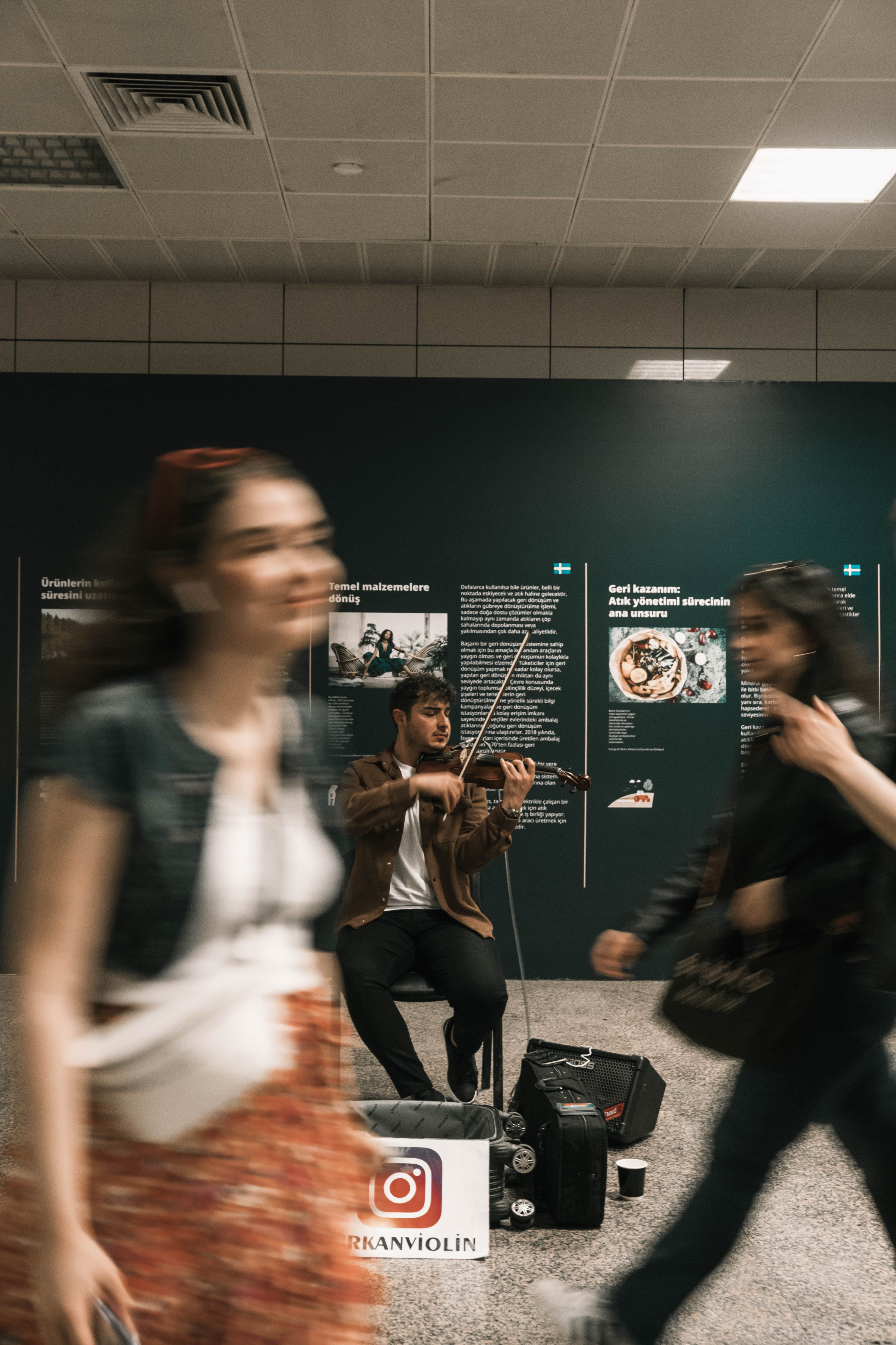 A violinist plays in a subway as commuters blur past, capturing urban motion and music.