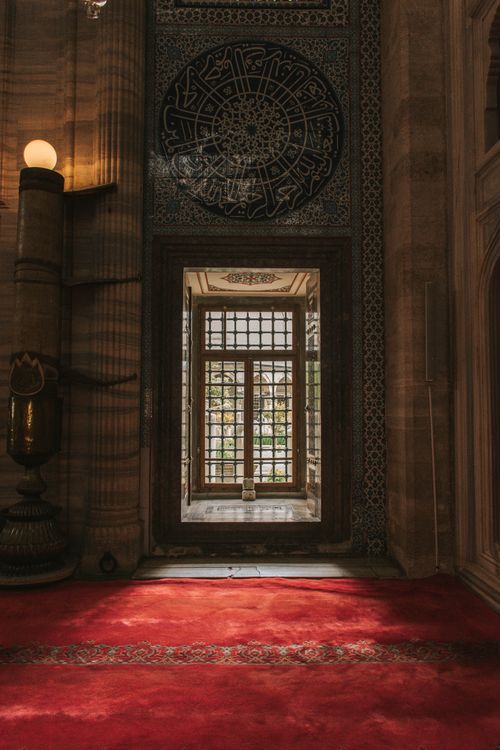 Free Explore the serene beauty of a mosque interior featuring intricate designs and vibrant red carpet. Stock Photo