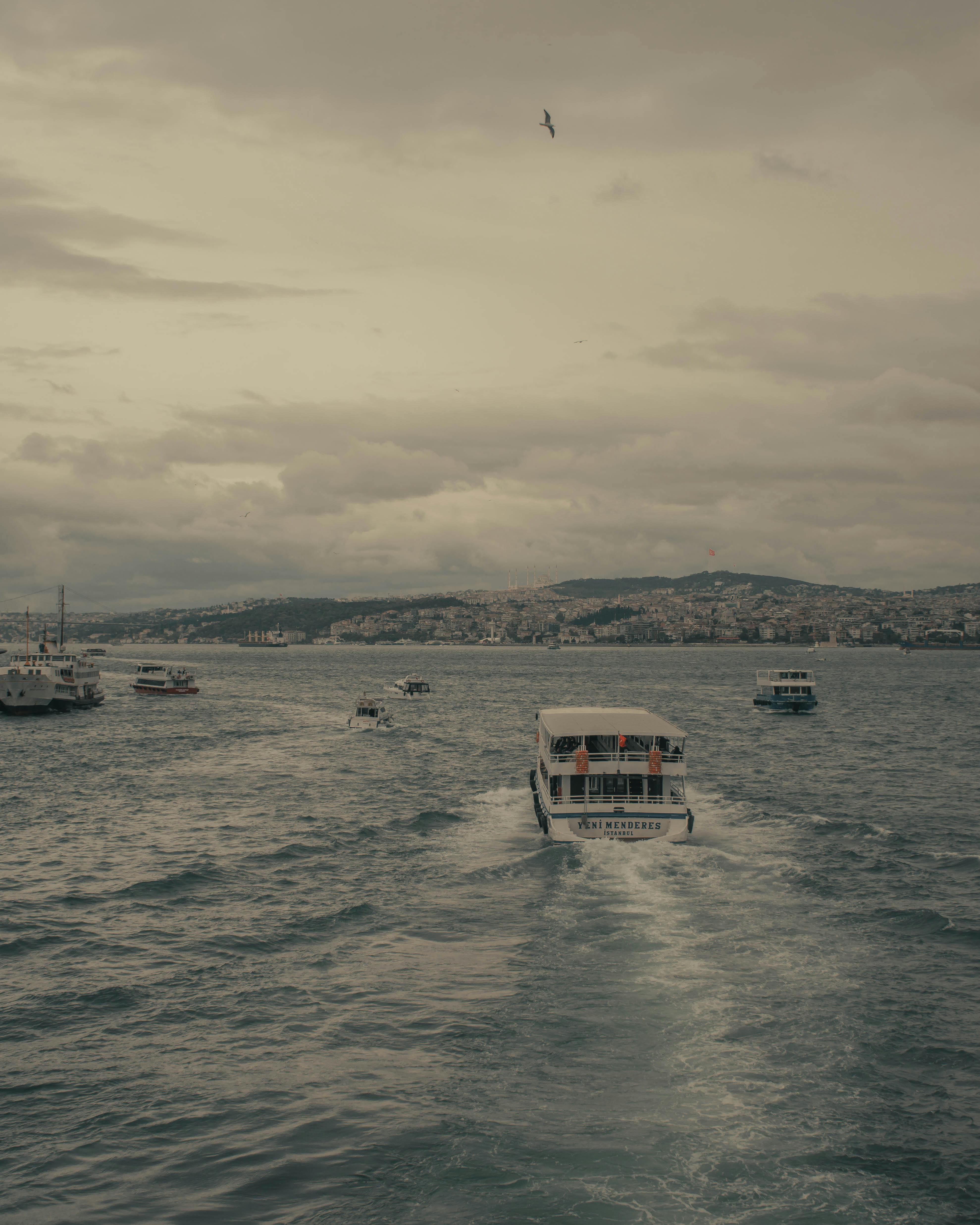 Boats on a serene sea with cloudy skies, creating a moody travel scene.