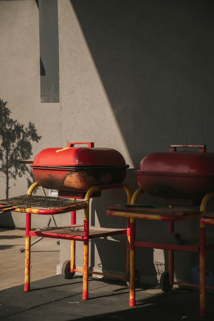Fotomural Parrillas rojas oxidadas proyectando sombras en un patio soleado.