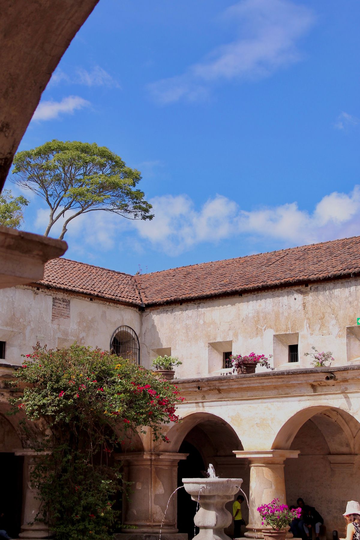 Colonial courtyard with arches, a fountain and bougainvillea under a blue sky