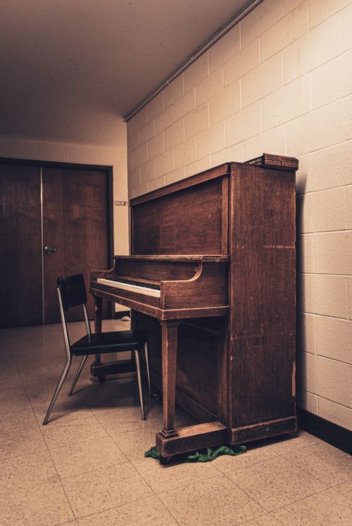 Free A retro-styled wooden piano in an empty room with vintage decor. Stock Photo