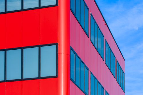 Free Bright red office building corner with windows against blue sky in Hoofddorp, Netherlands. Stock Photo