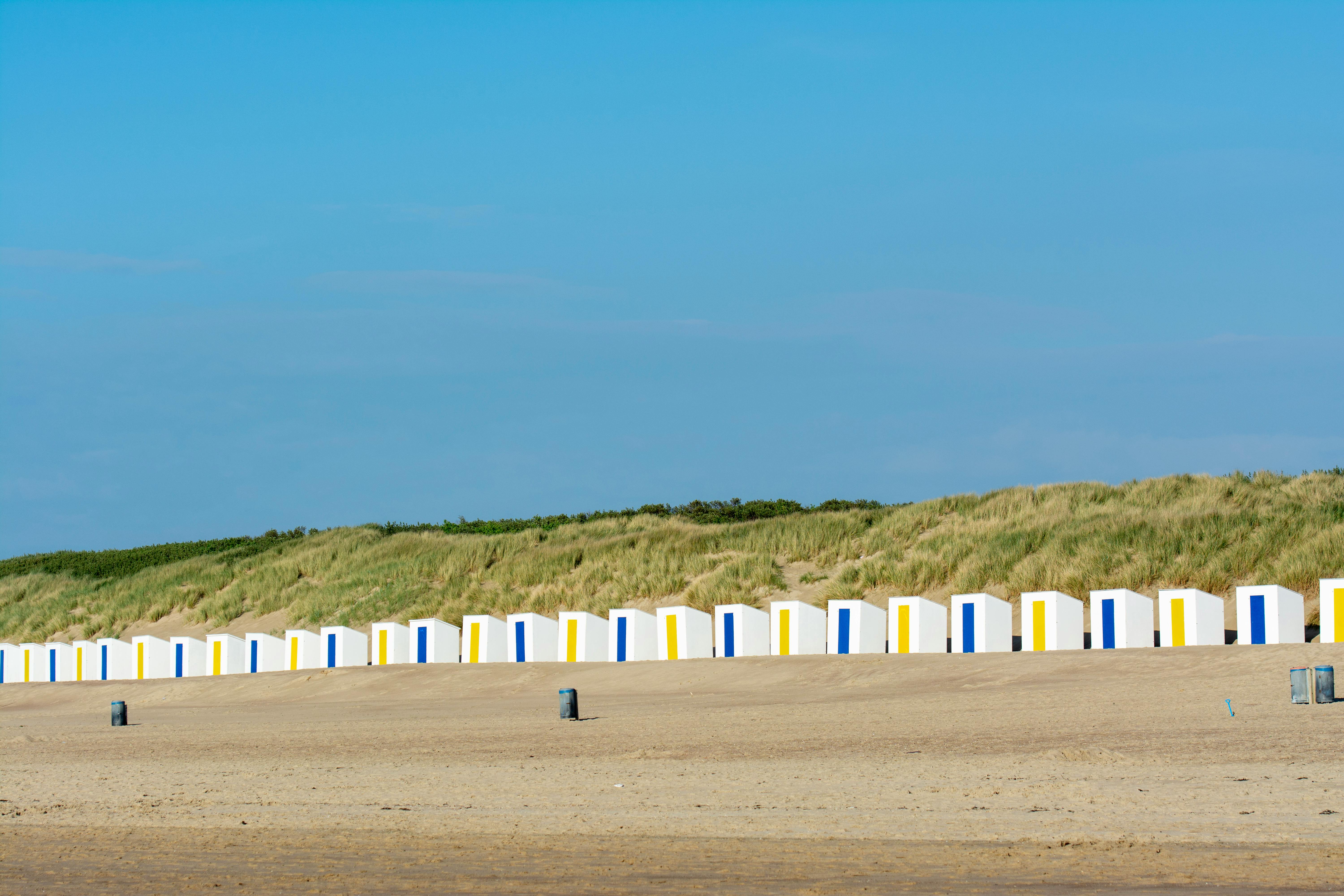 Row of vibrant beach huts against sandy dunes at Cadzand, Netherlands.