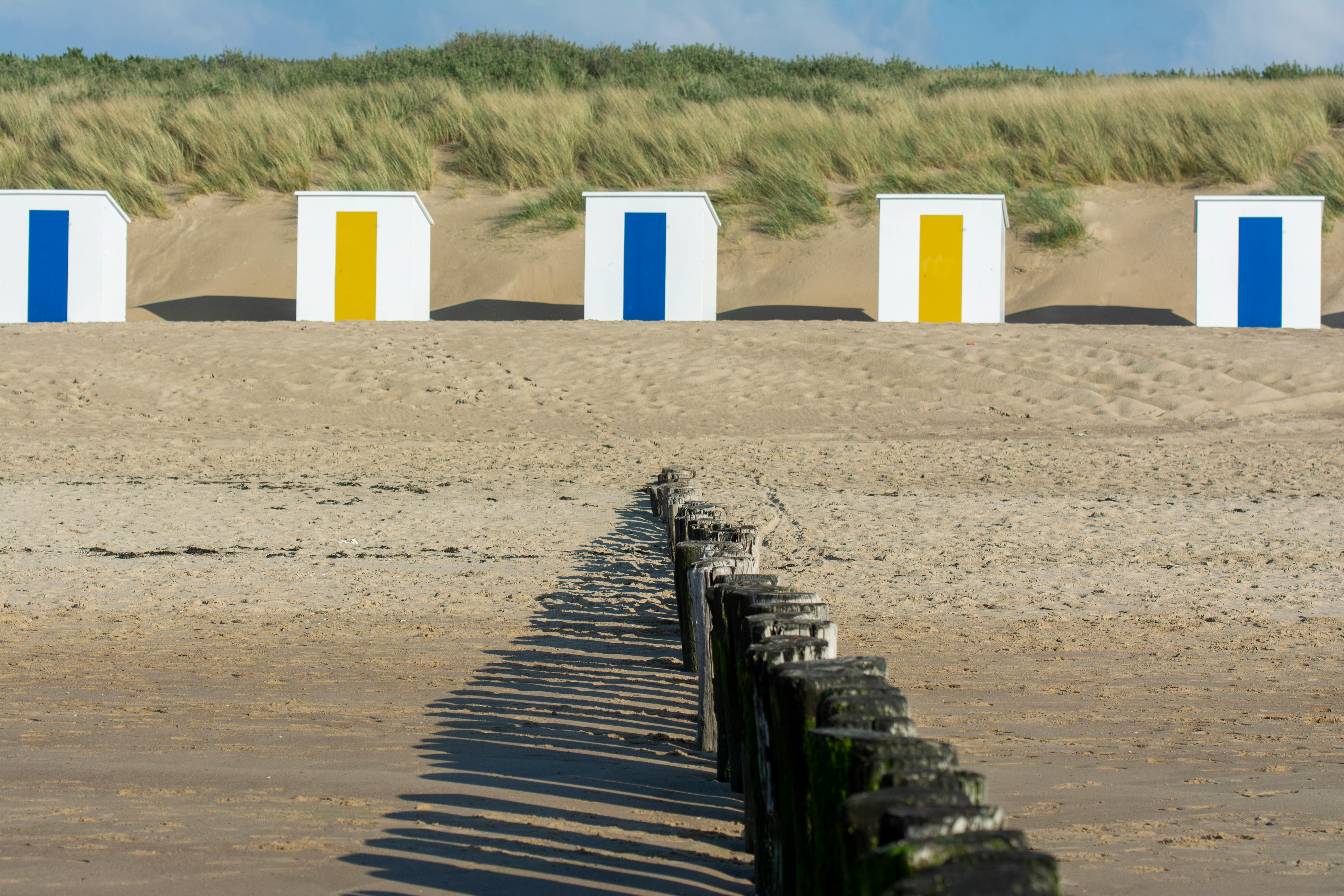 Vibrant beach sheds with wooden breakwater on the sandy shore of Cadzand, Netherlands.