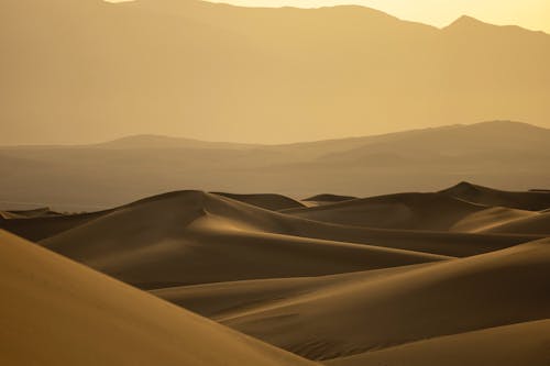 Dunes in Desert against Silhouette of Mountains