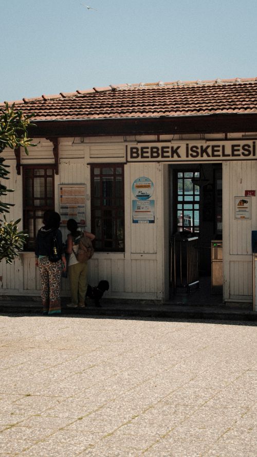Free People standing outside the Bebek Iskelesi ferry terminal in Turkey under a bright blue sky. Stock Photo
