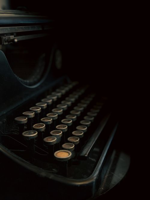 Free Close-up of an antique typewriter in dim lighting on a black background. Stock Photo