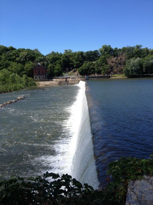 Free Idyllic view of waterfall at Clear Spring Dam with lush greenery and historic buildings. Stock Photo