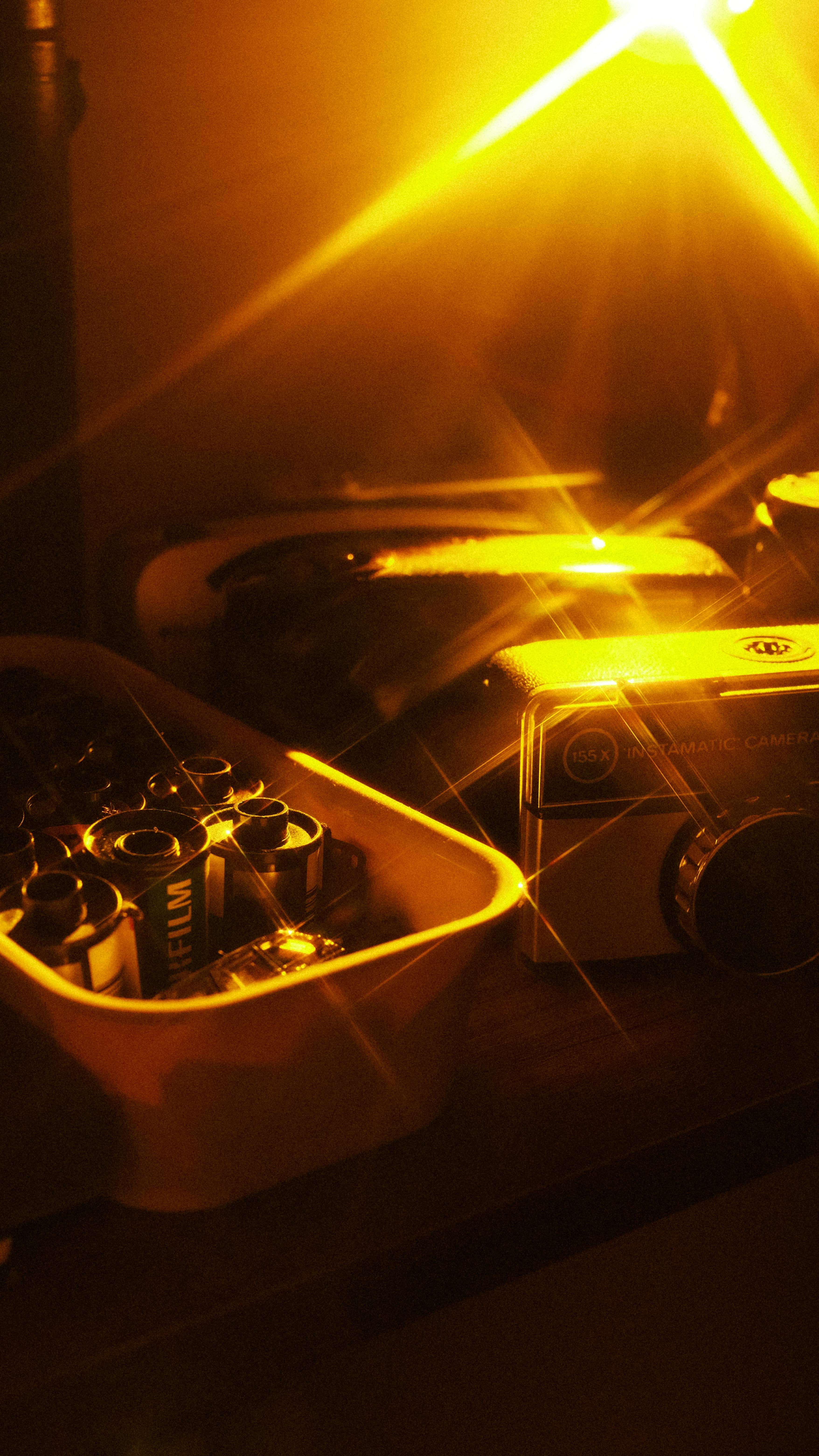 A vintage camera and film rolls illuminated by warm, golden light, conveying nostalgia.