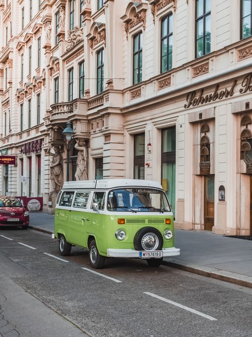 Free Green vintage Volkswagen van parked on a historic European city street during daytime. Stock Photo