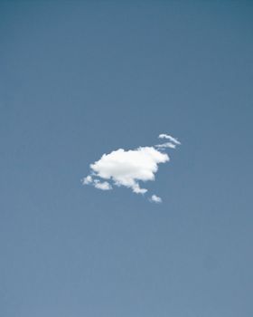 A single white cloud floating in a clear blue sky, showcasing nature's simplicity and beauty.