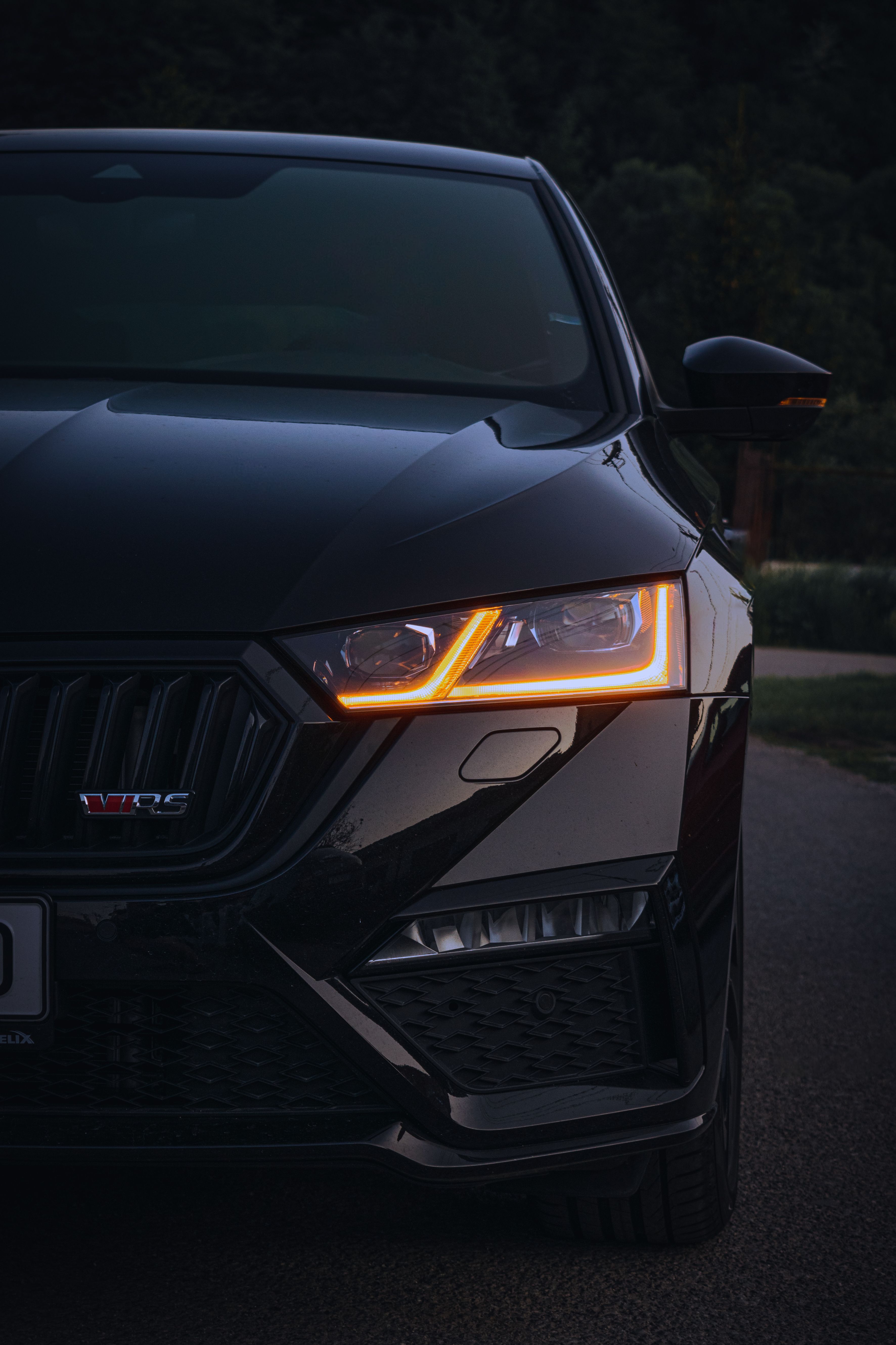 Farol de LED de um carro preto de luxo fotografado ao entardecer