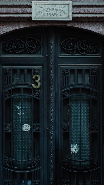Fotomural Un primer plano de una puerta vintage ornamentada con herrajes detallados y una fachada retro de 1909.