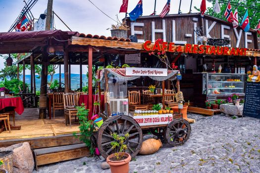 Charming rustic outdoor café featuring wooden furniture, colorful decor, and flags.