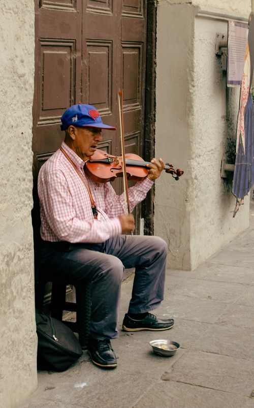 Free Elderly man playing violin on a city street, offering a soulful performance. Captured outdoors during the day. Stock Photo