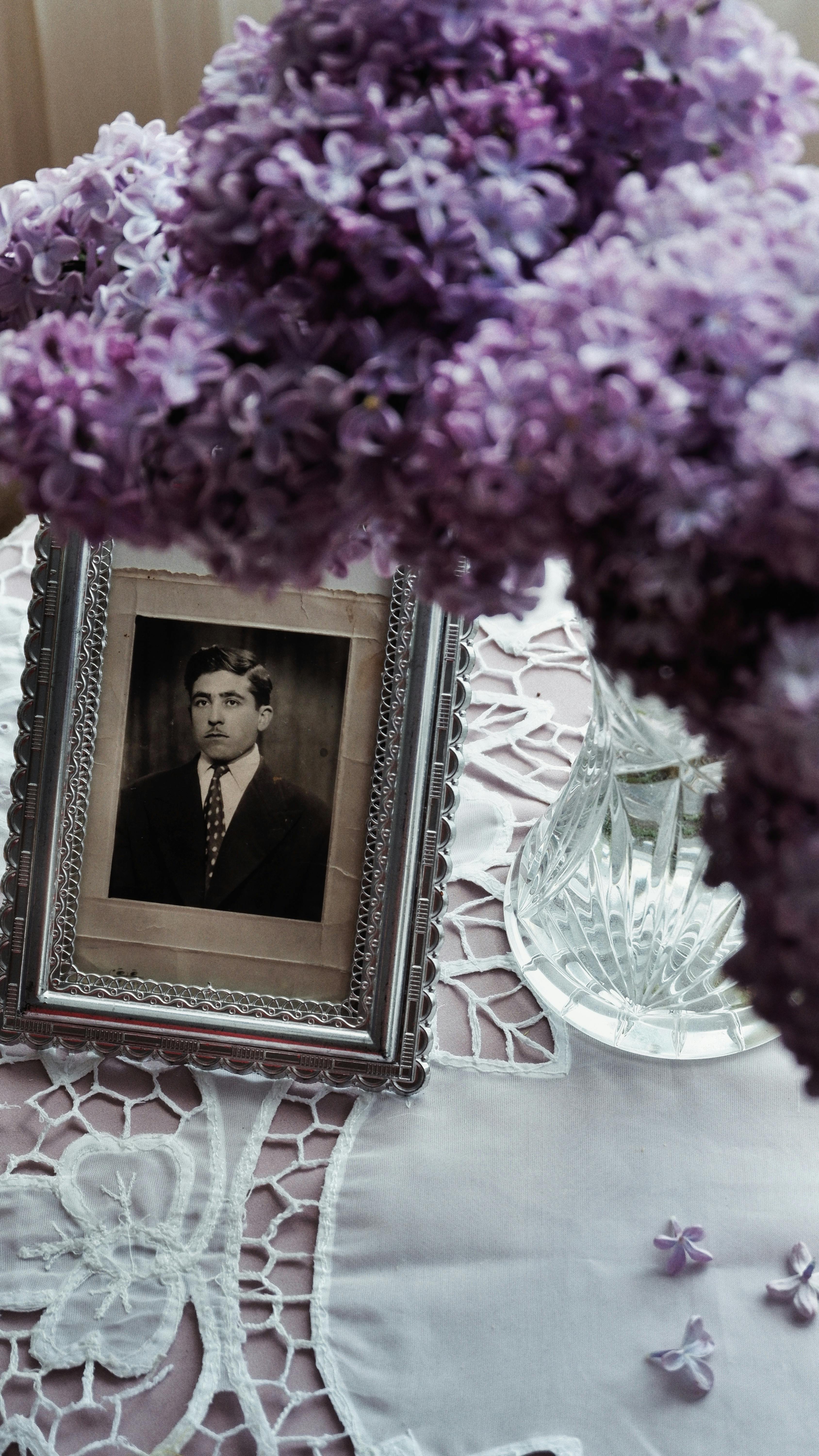A vintage photo surrounded by lilac flowers in a vase, evoking nostalgia.