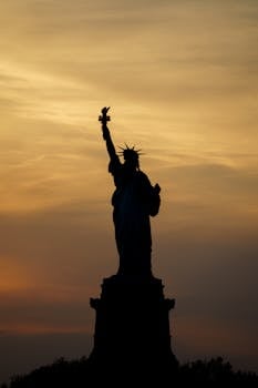 Dramatic silhouette of the Statue of Liberty against a sunrise in New York City.