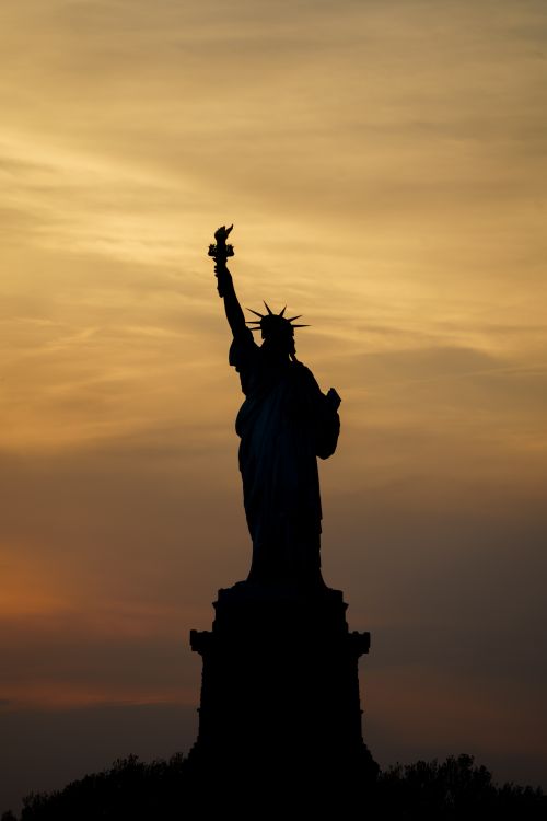 Free Dramatic silhouette of the Statue of Liberty against a sunrise in New York City. Stock Photo