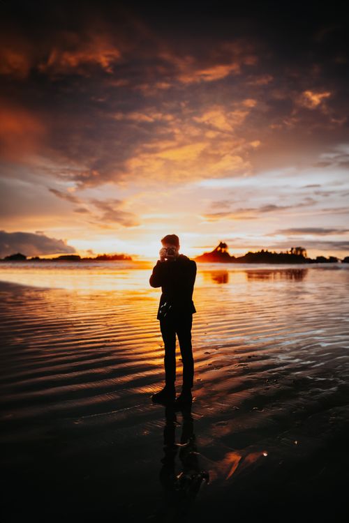 Free A solitary silhouette captures the sunset on a tranquil beach, evoking creativity and serenity. Stock Photo
