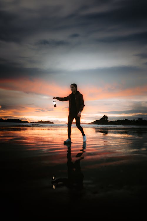 A Young Person Walking on the Beach at Sunset 