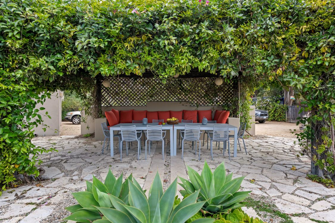 Sofá, cadeiras e mesa em pátio de jardim cercado por vegetação