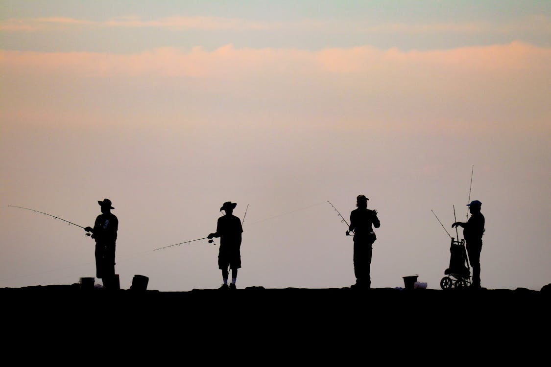 Stockvektorbilden Fisherman in a boat with a rod. Silhouette of a fisherman  at sunset. Sport fishing and hobby