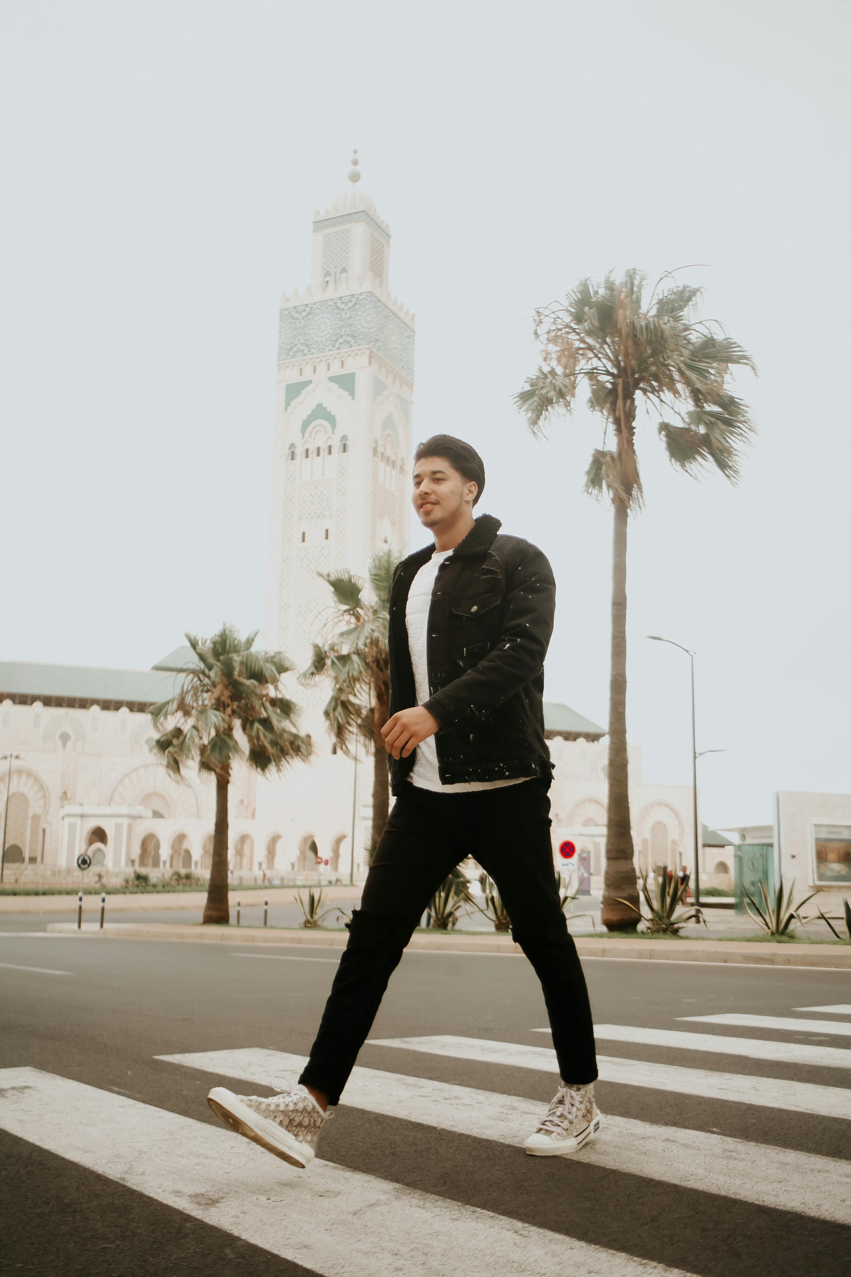 Casual young man walking on a zebra crossing near Hassan II Mosque in Casablanca.
