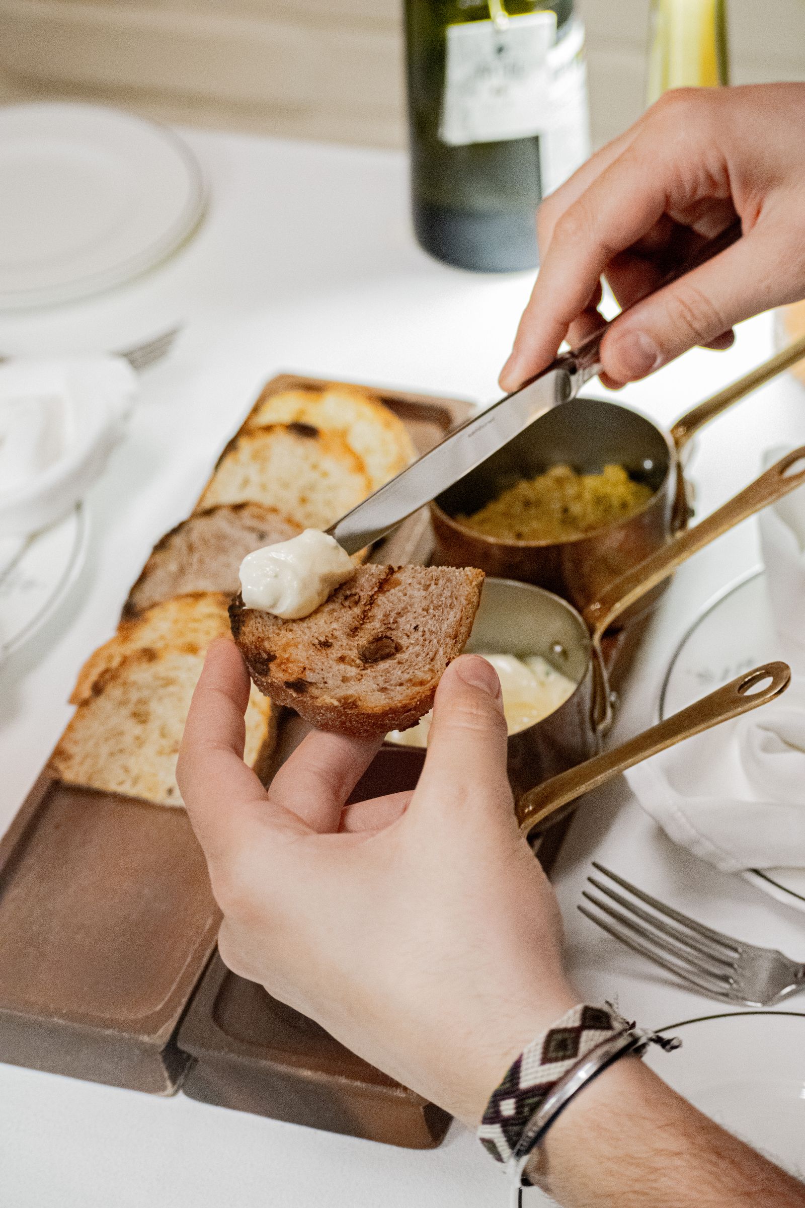 Person spreading butter evenly across a warm slice of artisan toast