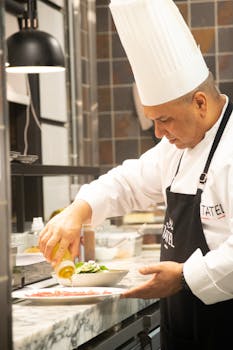 A professional chef focused on preparing a meal in a modern restaurant kitchen.