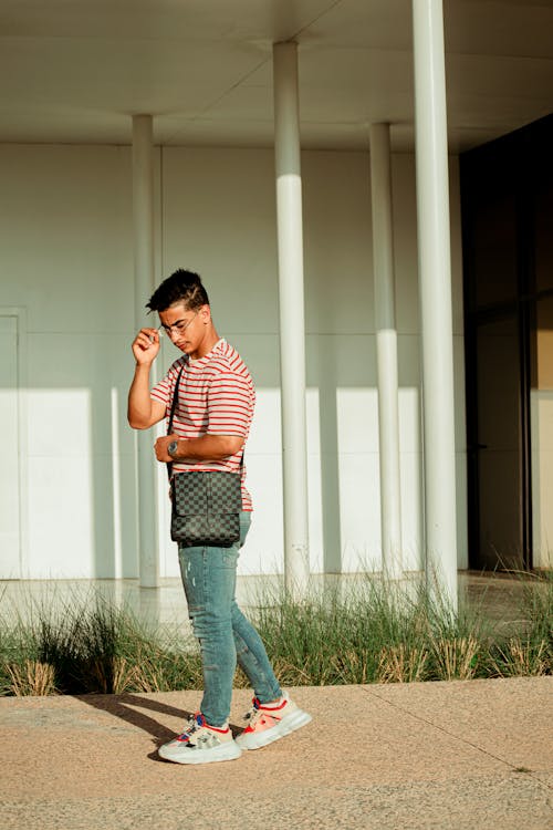 Young Man in Jeans and Striped T-shirt Standing Outdoors 