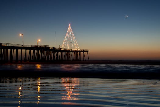 黄昏时分，平静的海面上倒映着码头明亮的灯光和月亮