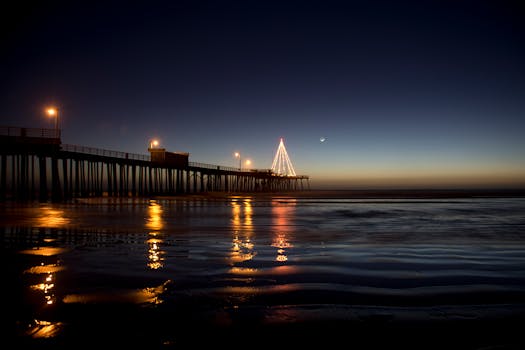 迷人的夜晚，码头现场点燃的灯光映照着平静的海水与上方的新月