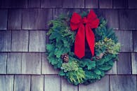 木墙上装饰着经典的圣诞花环，配有红色蝴蝶结和松果，营造出节日气氛