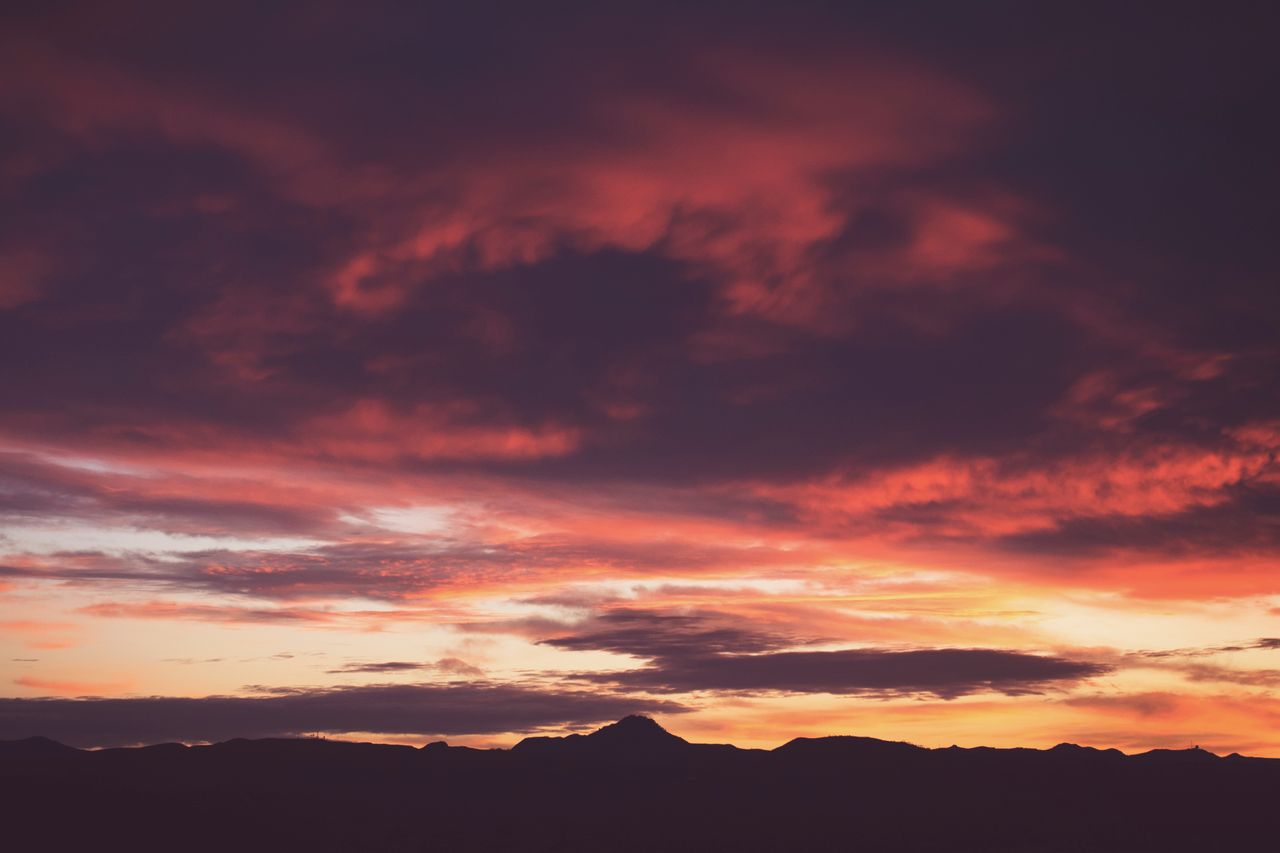 a breathtaking sunset over silhouetted mountains with vibrant cloudsca