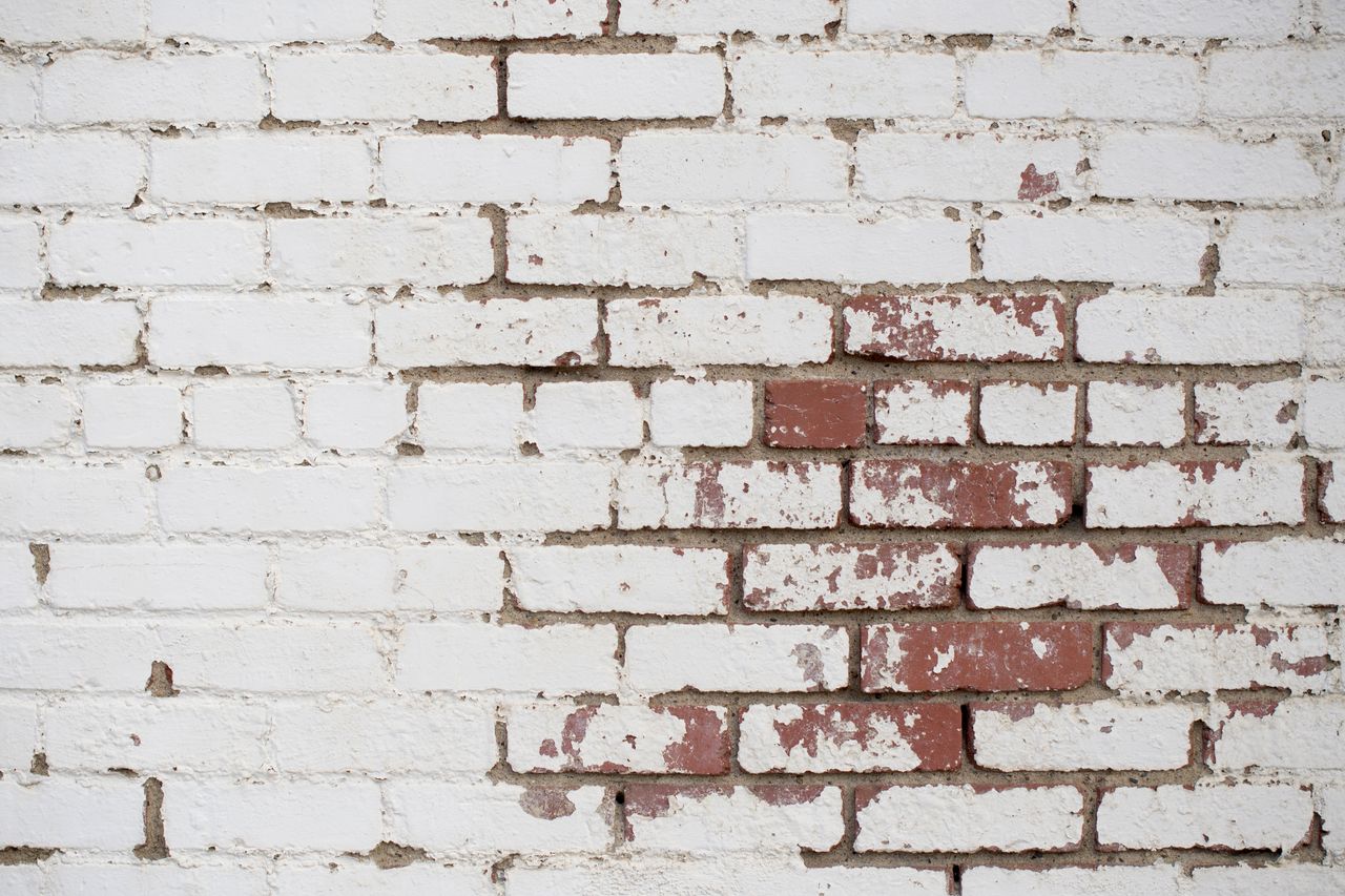 detailed texture of an old white brick wall with peeling paint and vis