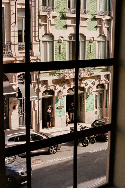 View of a Porto street through a window, showcasing classic architecture and street life.