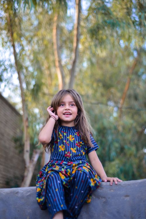 Free A young girl with long hair enjoying a sunny day outdoors, sitting under a tree. Stock Photo