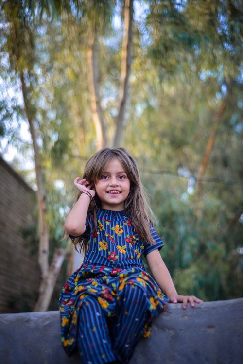 Free Portrait of a happy girl sitting outside amidst lush greenery in Punjab. Stock Photo