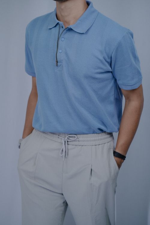 Free Man wearing a blue polo shirt and beige pants with hands in pockets. Stock Photo