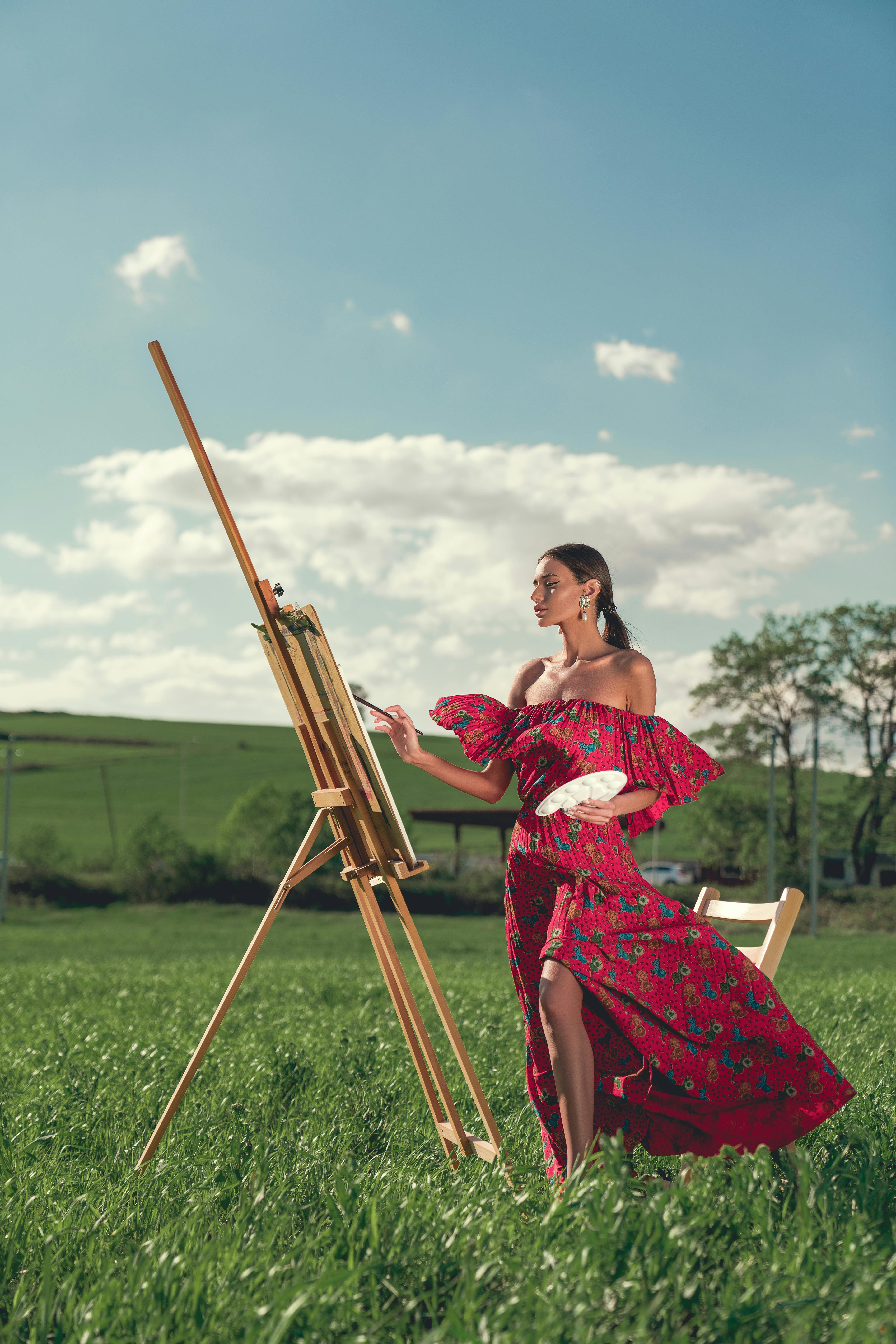 woman in red dress painting on grass