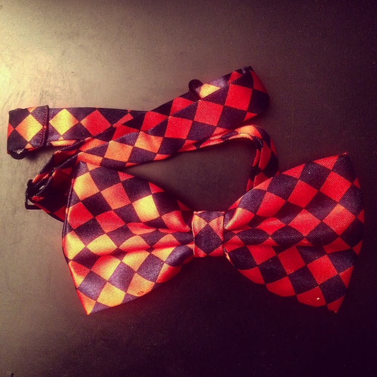 Free Red and Black Checkered Bow on Black Surface Stock Photo